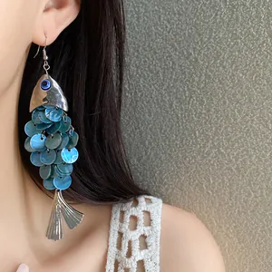 Détail de boucles d'oreilles en forme de poisson bleu avec pompons métalliques