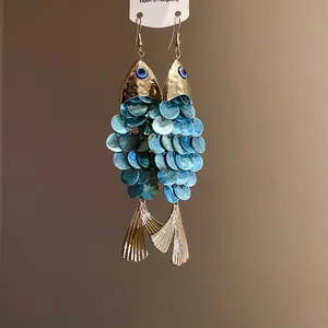 Gros plan de boucles d'oreilles vintage en forme de poisson avec écailles bleues et œil