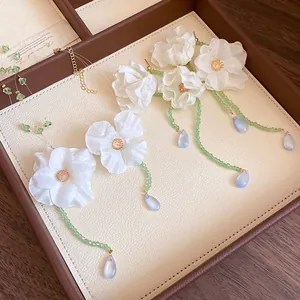 Detail view of elegant white fabric flower earrings and necklace set with green beads