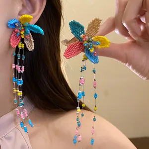 Close-up of colorful handmade beaded flower tassel earrings worn by an Asian model.