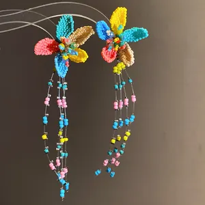 Detailed view of handmade colorful beaded flower earrings with long Bohemian style tassels