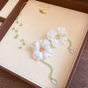Detail view of stainless steel fabric flower jewelry set with green beads on leather tray