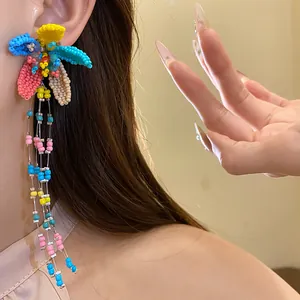 Detailed close-up of colorful beaded flower earrings with long fringe tassels on Asian model