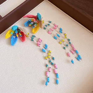 Close-up of vibrant handmade beaded flower earrings with long tassels on white tray