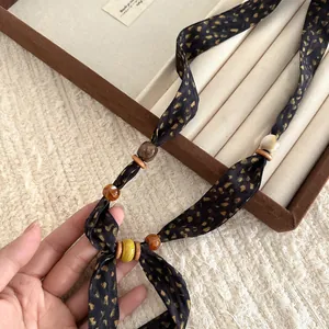 Close-up detail of a handmade fabric printed scarf necklace featuring artistic beads