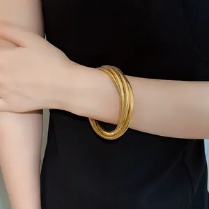 Close-up view of a minimalist gold multi-layer spring bracelet worn on a wrist.