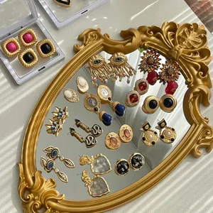 Elegant collection of French vintage gold earrings displayed on a luxury gold mirror tray.