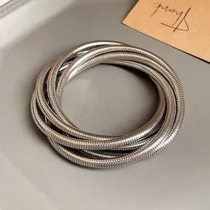 Detailed close-up of minimalist silver multi-layer spring bracelet with metallic luster