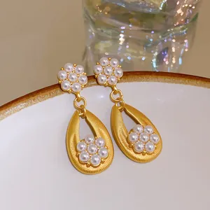 Close-up of French vintage floral pearl earrings with brushed gold texture