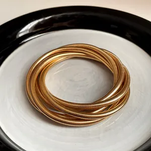 Close-up of multi-layer gold spring bracelets with metallic ribbed texture on a plate.