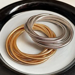 Close-up detail of multi-layered gold and silver metallic spring bangles on a ceramic plate.