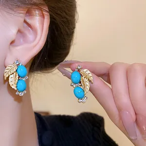 Detail of vintage French style earrings with gold leaves and blue oval turquoise-like stones