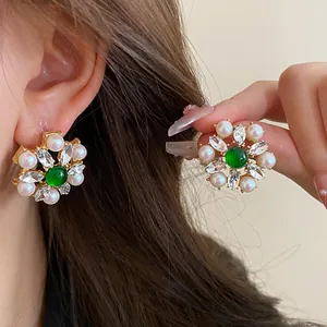Detailed view of French vintage floral earrings with pearls, crystals, and green center