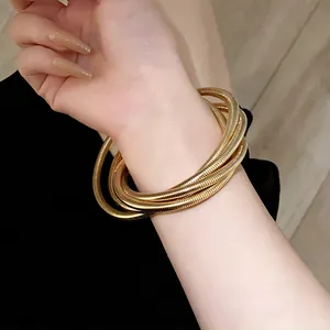 Close-up of gold multi-layer spring-textured minimalist bracelet on wrist.