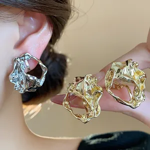 Detailed view of irregular wrinkled geometric gold and silver clip-on earrings