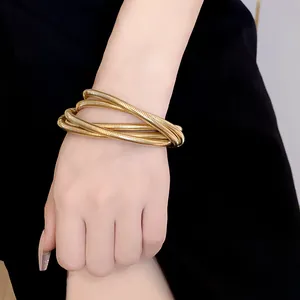 Detailed view of a golden multi-layer spring bracelet worn on a female wrist accessory