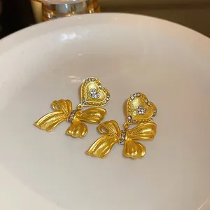 Detailed macro view of vintage gold-plated heart and bow earrings with crystals.