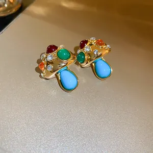 Macro view of vintage gold-toned mushroom earrings featuring colorful stones and rhinestones