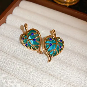 Detailed macro shot of vintage French style gold-plated leaf earrings with blue crystals