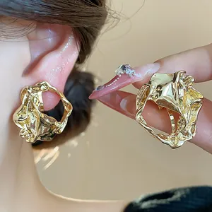 Close-up view of elegant gold geometric crumpled ear clips with liquid metal texture