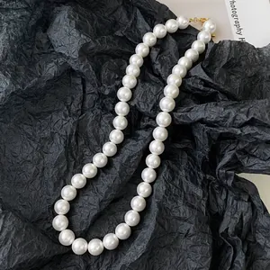 Élégant collier de perles blanches avec fermoir doré sur fond de papier noir froissé