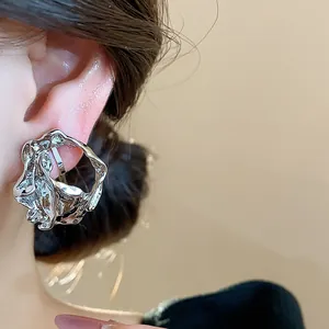 Close-up detail showing a silver geometric wrinkled ear clip worn on a model's ear