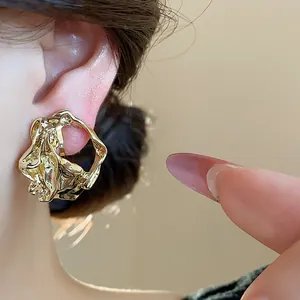 Detail shot of 18k gold-plated crumpled geometric clip-on earring worn on the ear