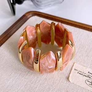 Dettaglio di un bracciale vintage in acrilico con motivo marmo salmone e barre dorate