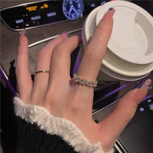 Detailed shot of sparkling baguette zircon ring and gold band worn on a manicured hand.