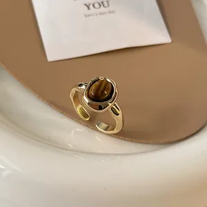 Close-up detail of a vintage tiger eye stone ring with an irregular gold open band design.