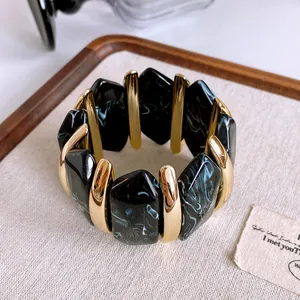 Dettaglio ravvicinato di un bracciale vintage in acrilico marmorizzato con elementi oro