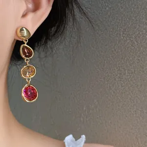 Close-up of multi-colored stone drop earrings with gold finish in French vintage style.