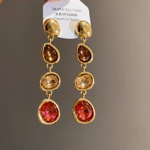 Detailed macro shot of vintage French style drop earrings with multi-colored crystals.