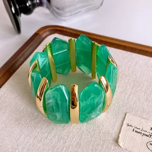 Dettaglio di un braccialetto vintage in acrilico marmorizzato verde con inserti oro
