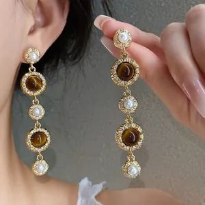 Detailed view of French vintage dangling earrings with pearls and tiger-eye stones