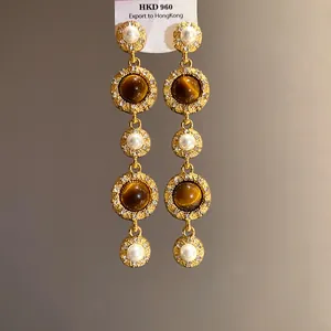Close-up of elegant French palace style long earrings with pearls and brown gemstones