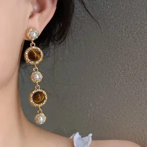 Detailed close-up of French court style pearl and tiger eye tassel earrings on a model.
