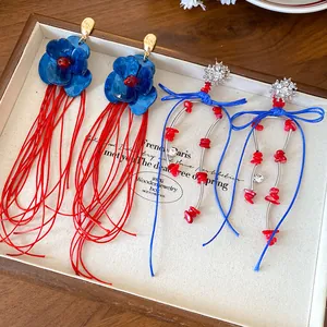 Detailansicht von Vintage-Ohrringen mit blauen Acrylblumen und Schleifenquasten in einer Box