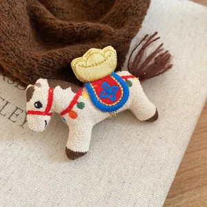 Primer plano de un broche de caballo de tela con bordado de lingotes de oro para regalos
