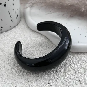 Detailed macro view of a glossy black resin open cuff bangle on a white minimalist background