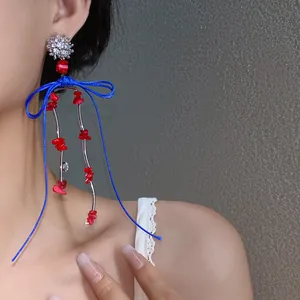 Nahaufnahme von Retro-Ohrringen mit blauer Schleife und roten korallenartigen Perlen