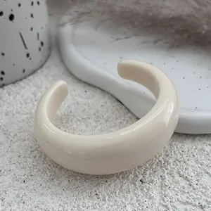 Detailed close-up of a minimalist cream resin open cuff bracelet with polished finish