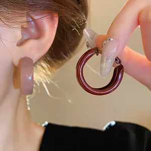 Close-up view of minimalist retro enamel hoop earrings in burgundy and nude pink shades