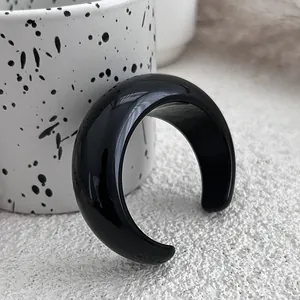 Close-up of a glossy black chunky resin open bangle with a modern C-shaped design