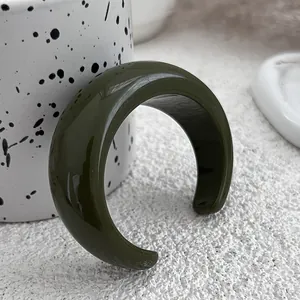 Close-up of olive green acrylic cuff bracelet with glossy finish on textured surface