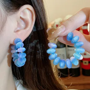 Pendientes de aro con cuentas de resina azul vibrante y aguja de plata para un look moderno.
