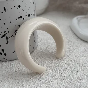 Close-up of minimalist cream acrylic geometric open cuff bracelet on textured background