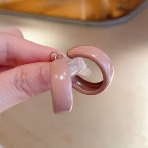 Detailed close-up showing the glossy pink enamel finish and retro C-shape hoop earring design