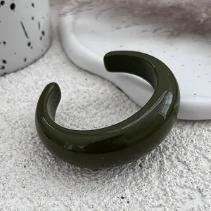 Detail view of a thick dark green resin open bangle showing its smooth glossy texture