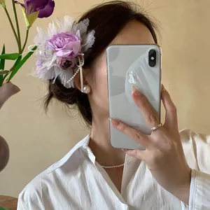 Close-up detail of an elegant purple floral shark hair clip worn by a model in a mirror